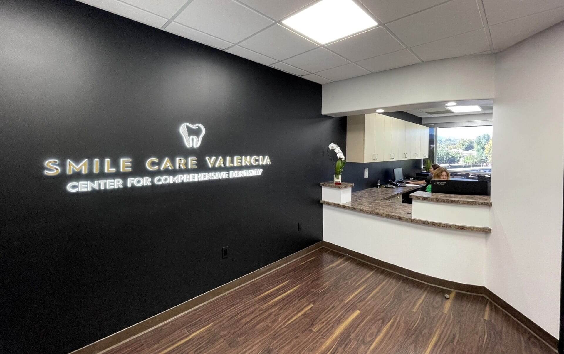 Reception area with the Smile Care Valencia logo wall and front desk