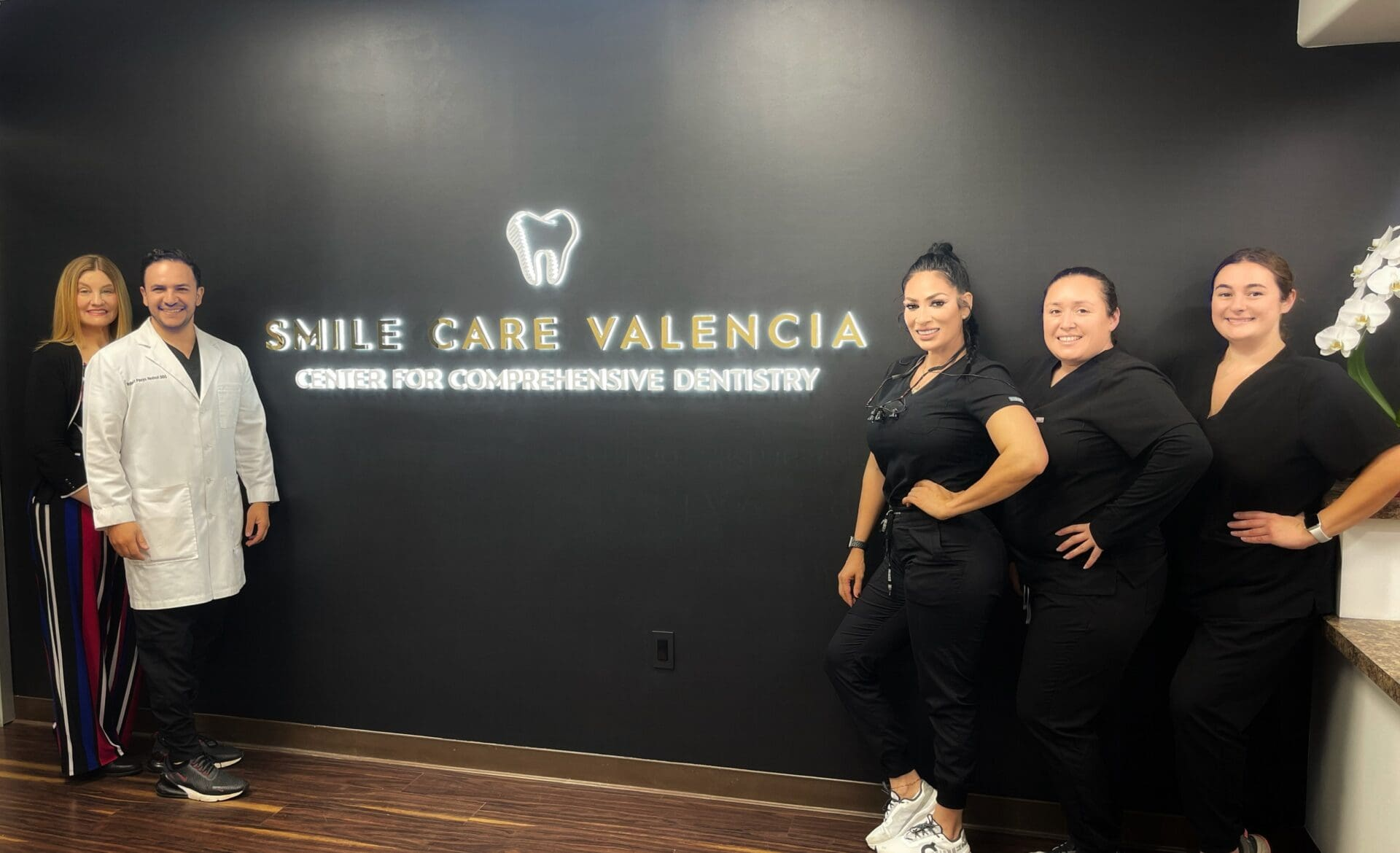 The Smile Care Valencia team in front of the illuminated practice logo